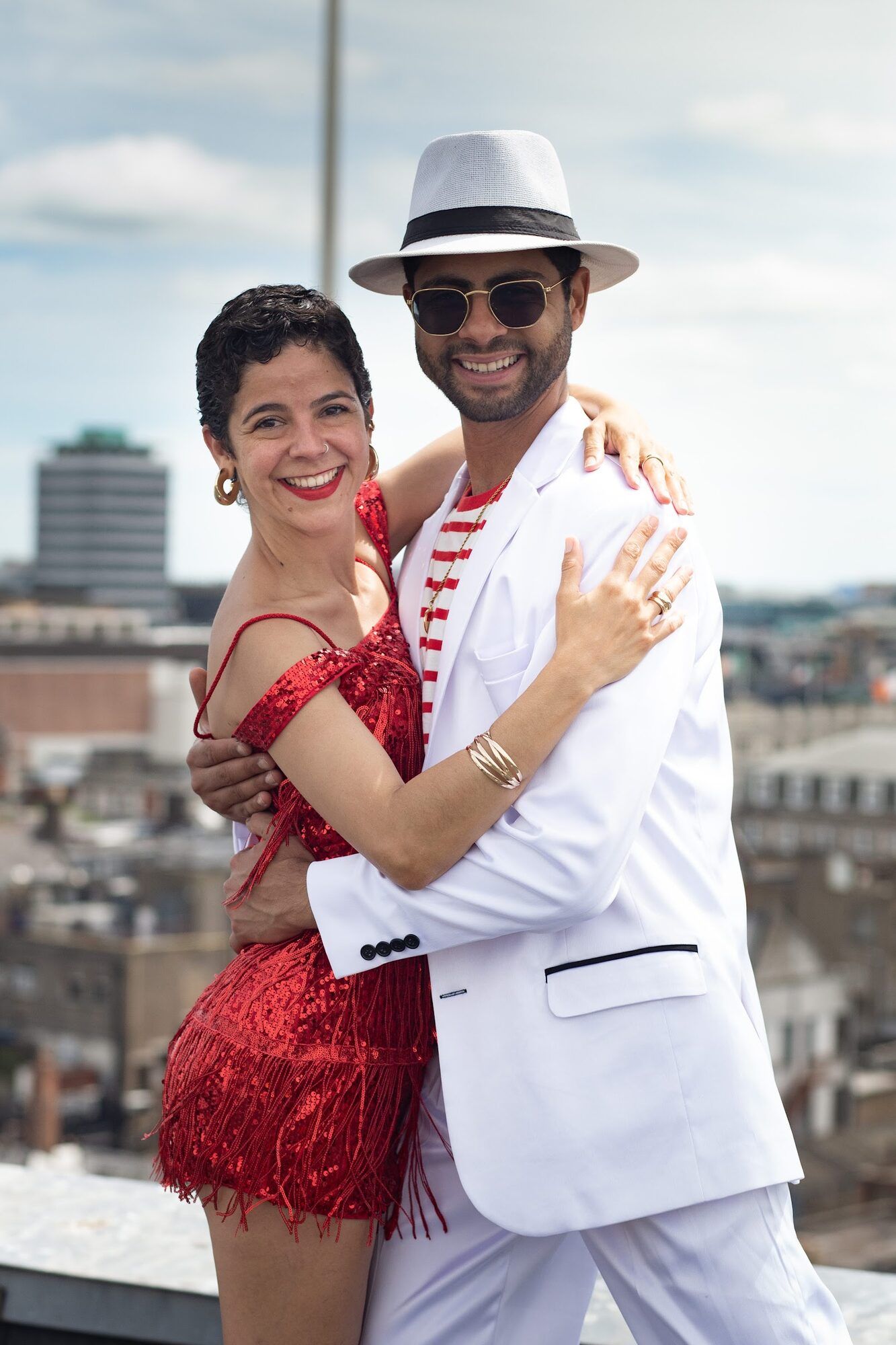 Dancer in a white suit embracing a dancer in a red sequinned dress