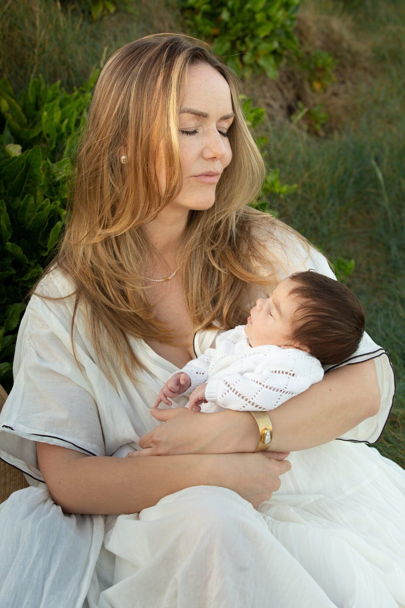 Mother in white cradling her baby