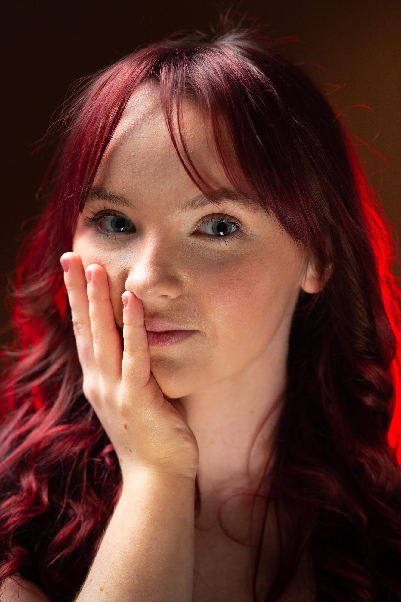 Woman with red hair, hand on her cheek, red light