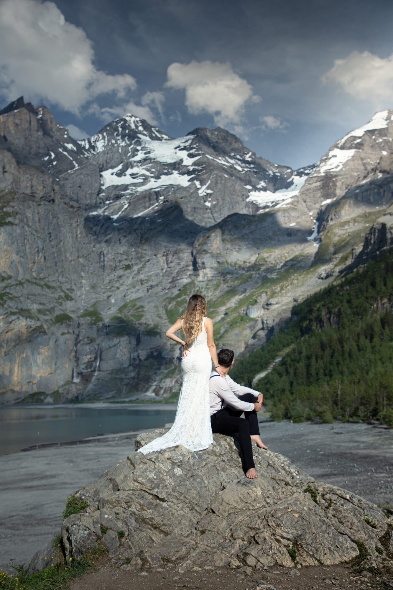 Couple on a large rock, snowy peaks above