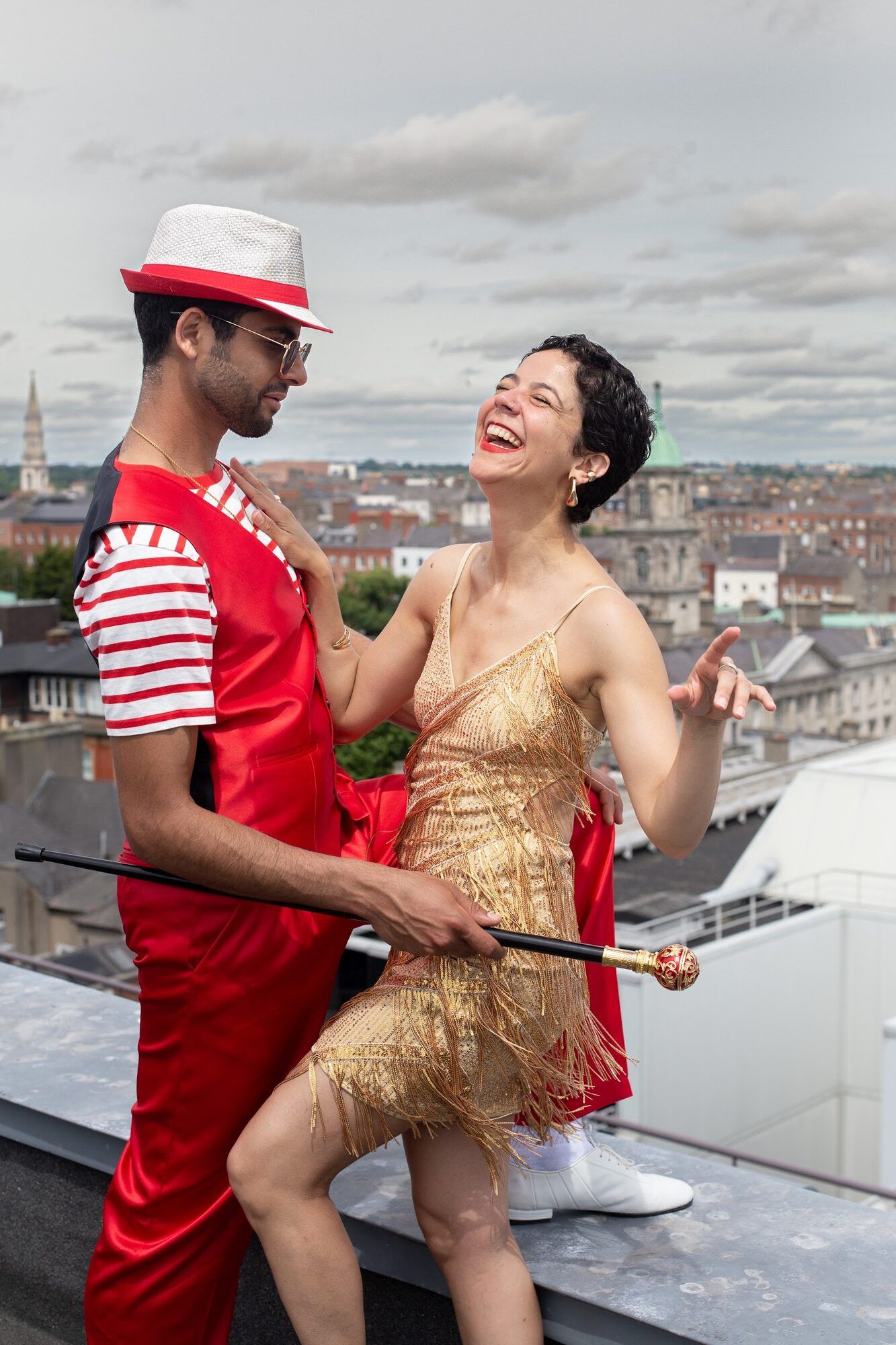 Dancer in red with a cane and a dancer in gold laughing