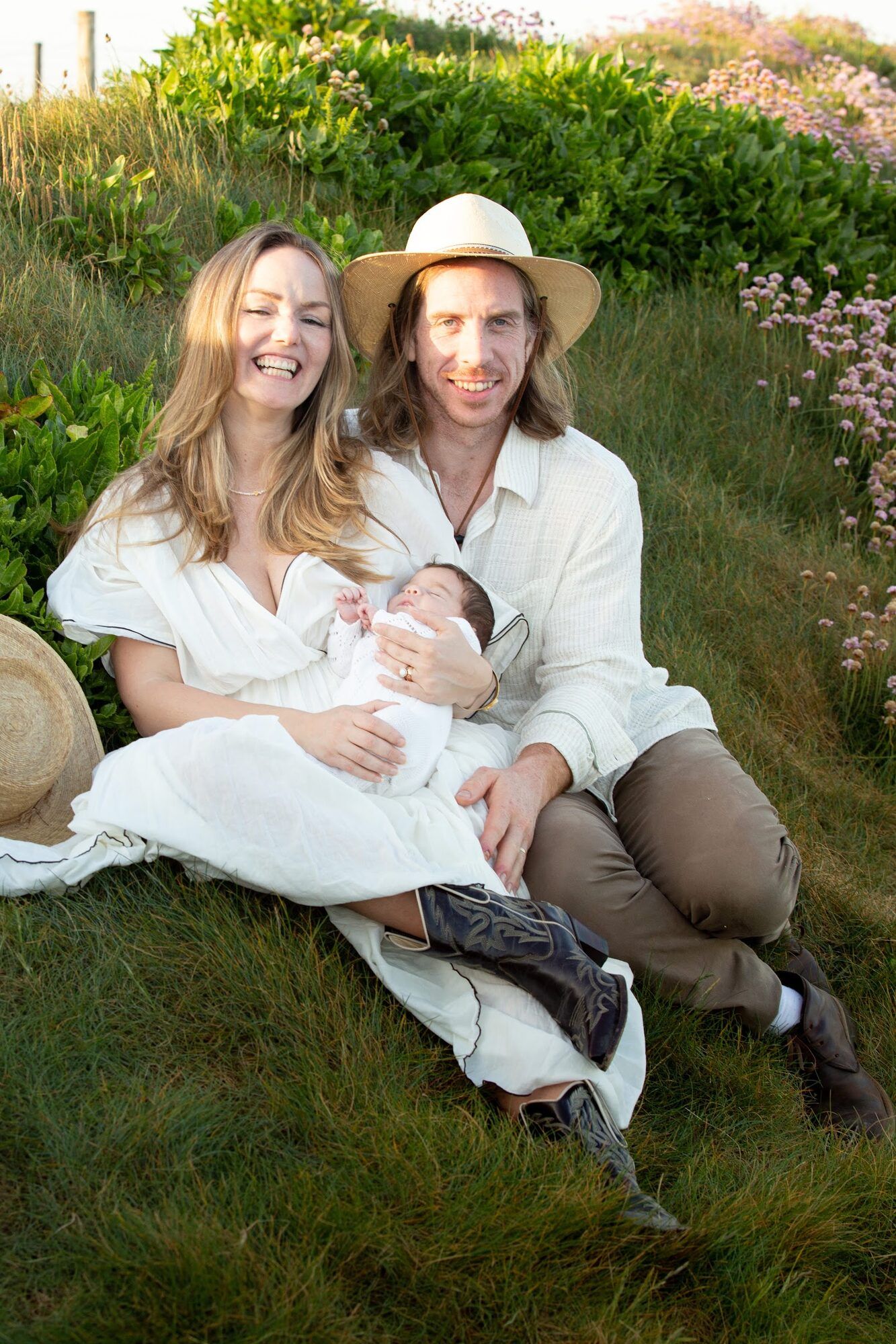 The family sitting on a grassy slope, laughing
