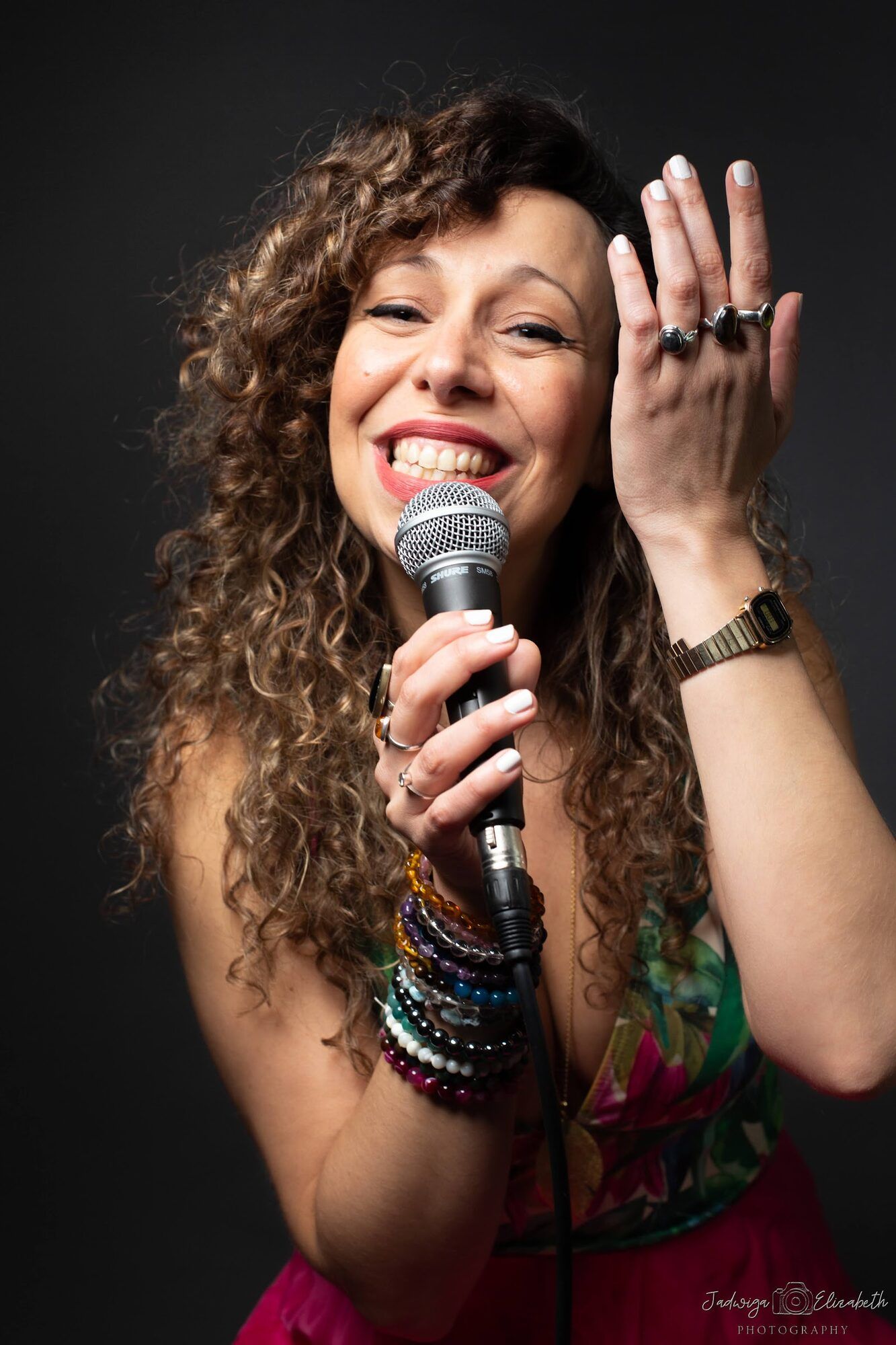 Singer with curly hair laughing into a microphone