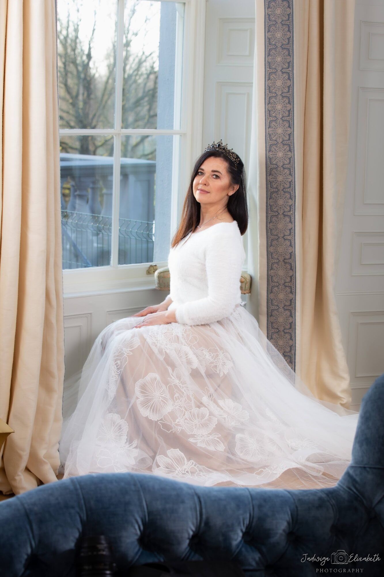 Woman in a white lace dress by a tall window