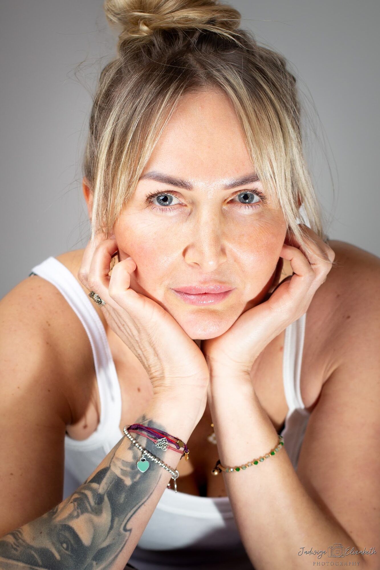 Blonde woman with her hair in a bun, chin on her hands