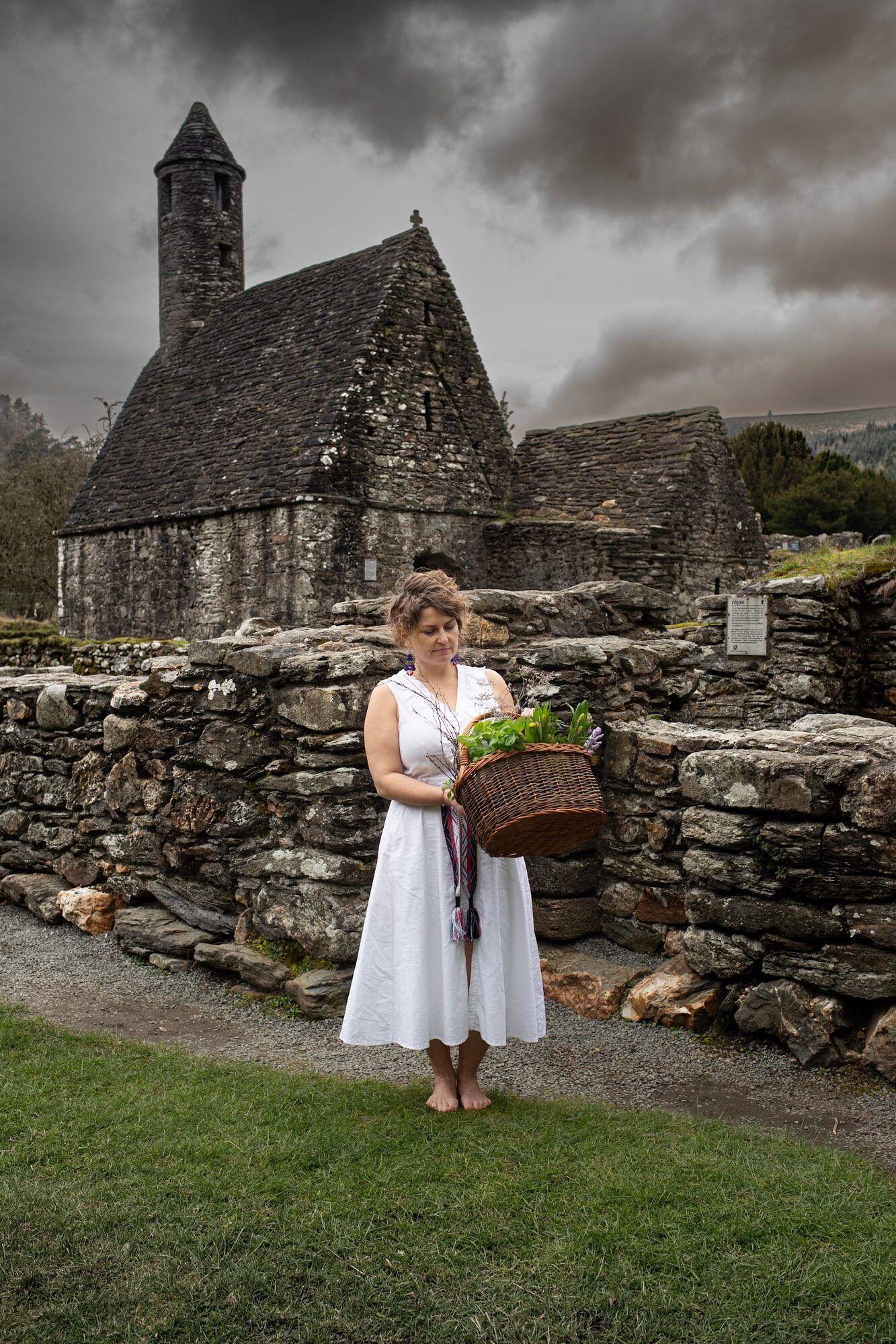 Woman in white with a basket by an old stone church