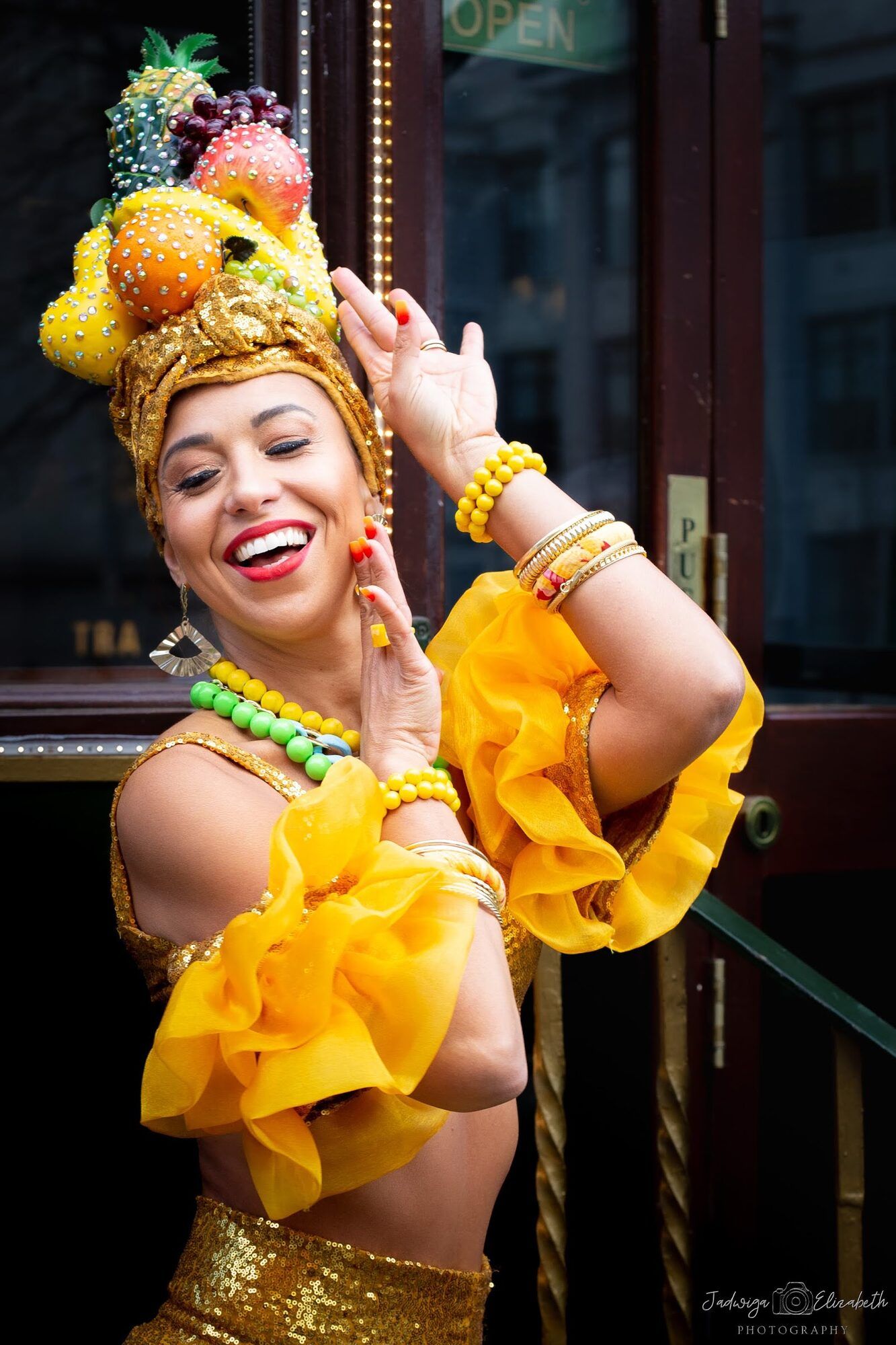 Dancer in yellow ruffles and a fruit headdress, laughing
