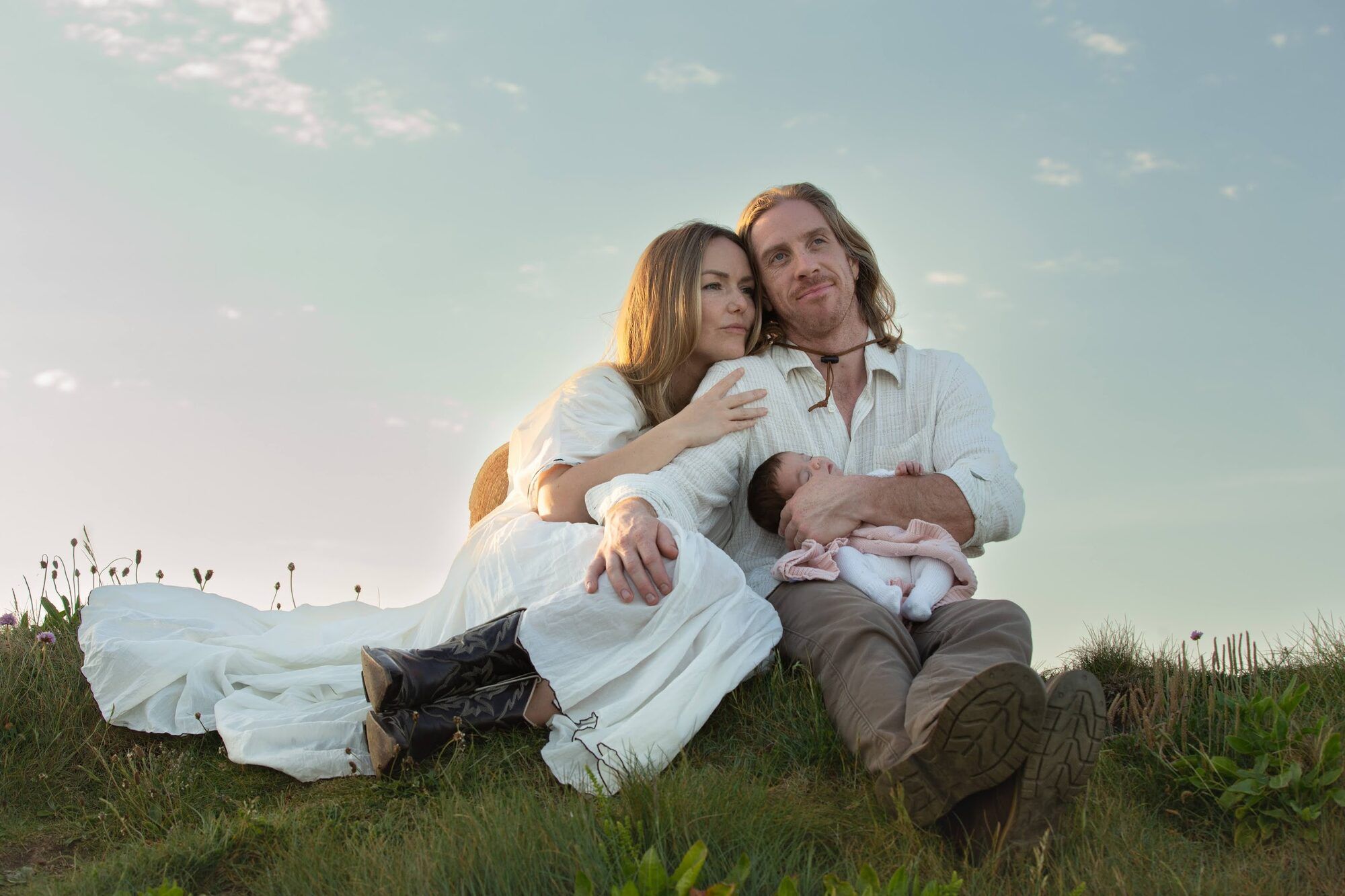 The family resting on the grass under an evening sky