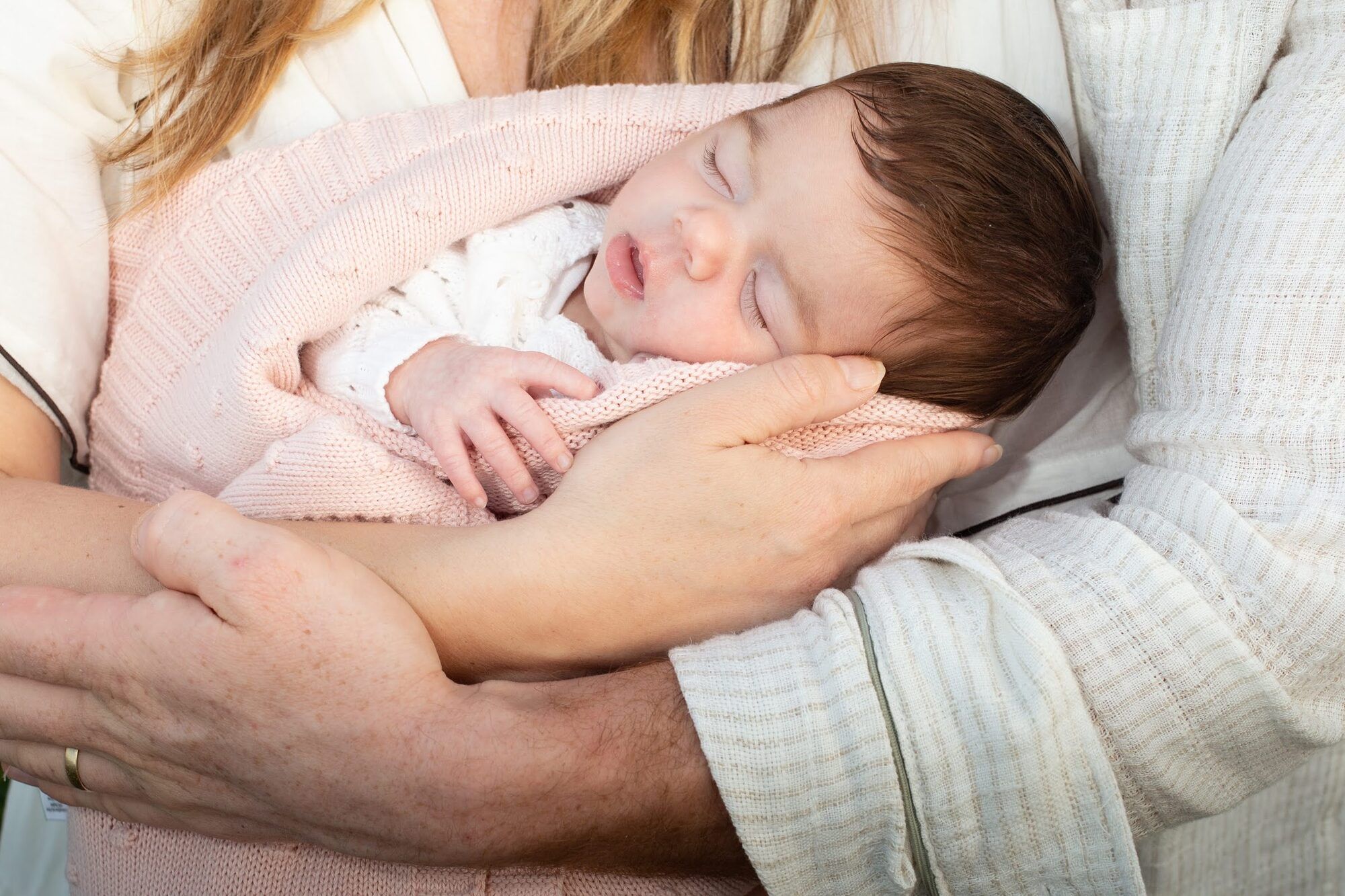 Close-up of the baby asleep on a parent’s arm
