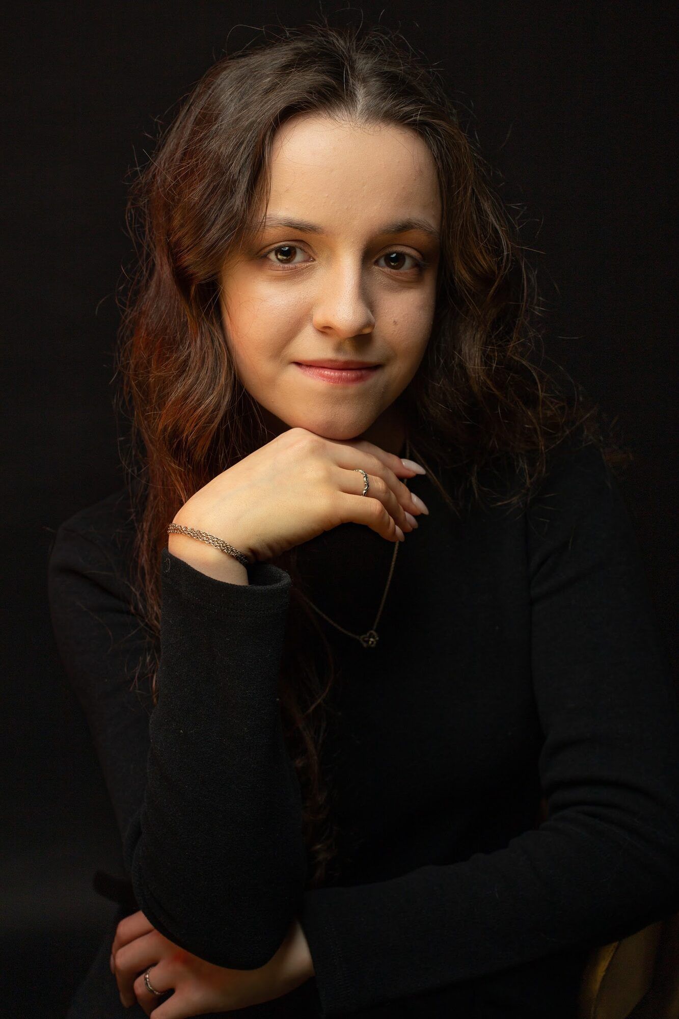 Young woman with dark curls, chin on her hand