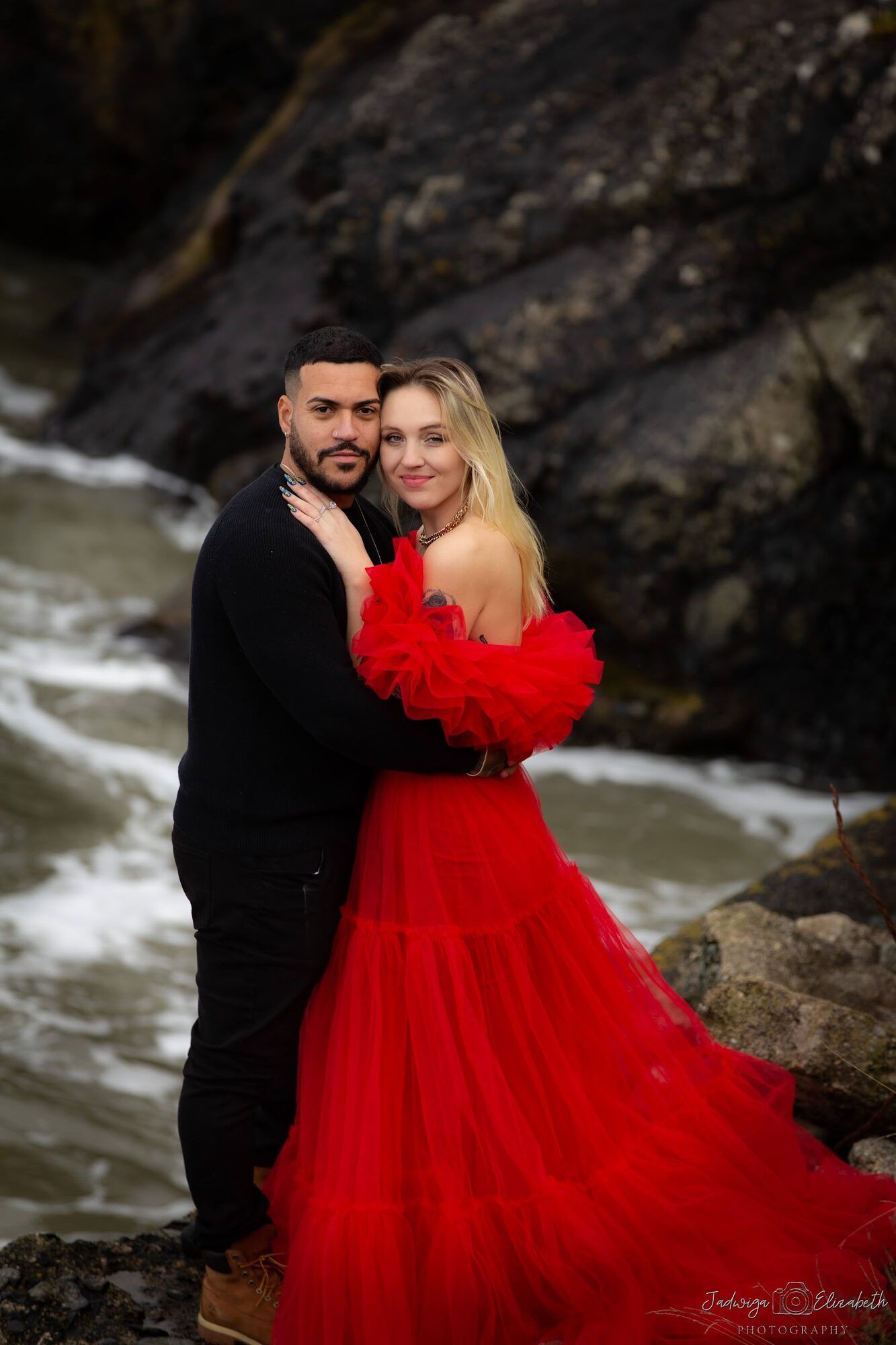 Embracing on the rocks, red gown