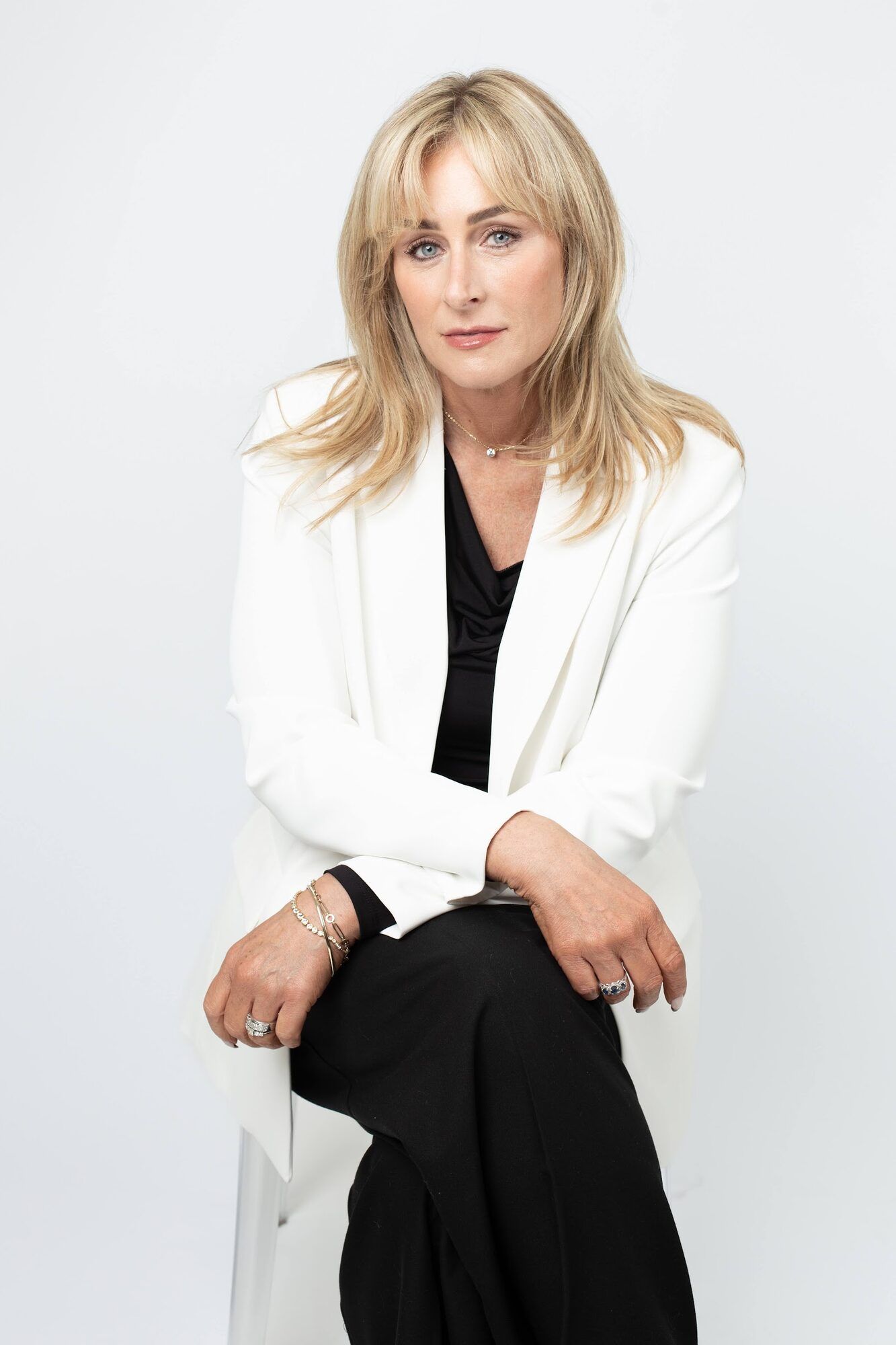 Woman in a white jacket, seated, light backdrop