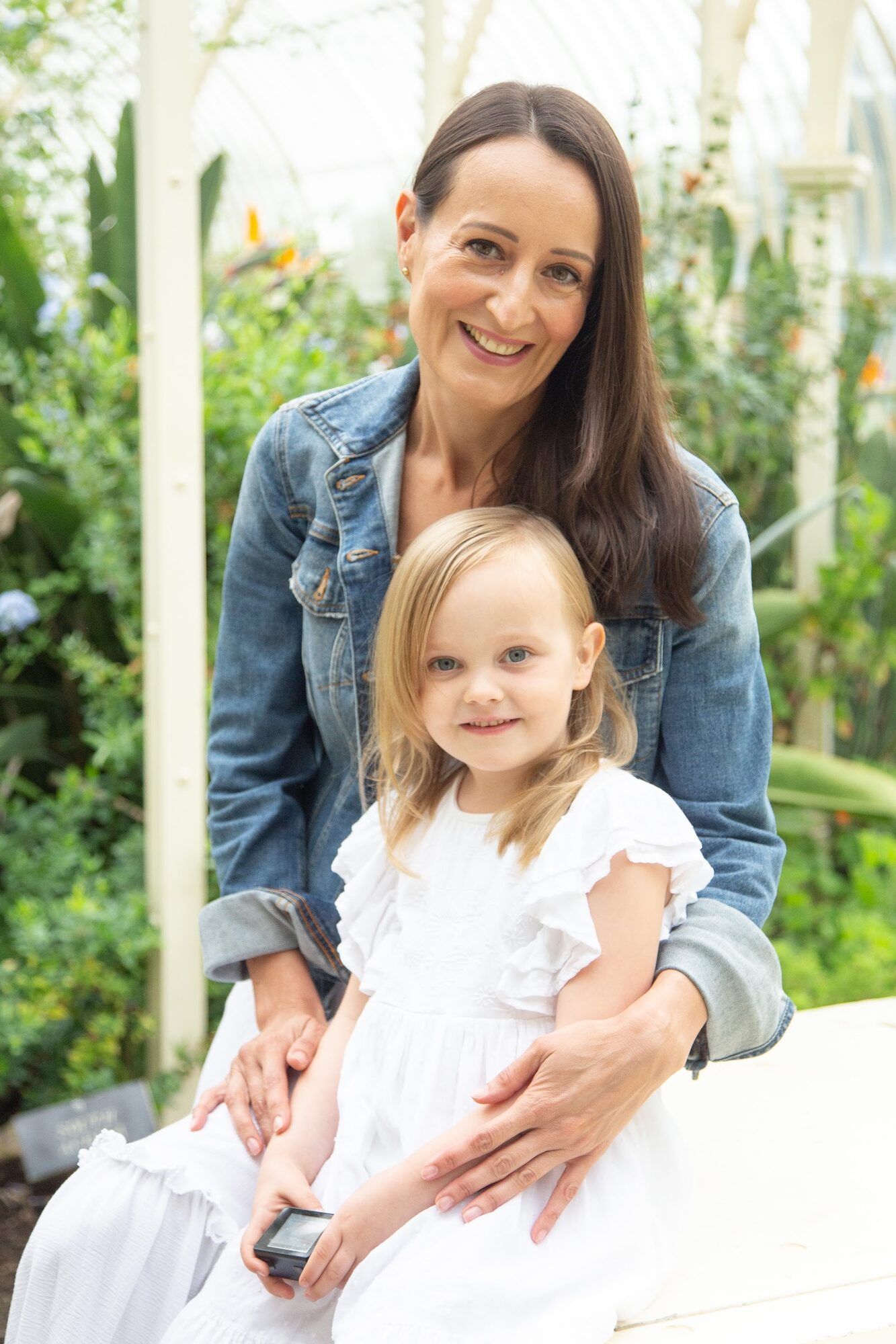 Mother and little girl in white in a garden