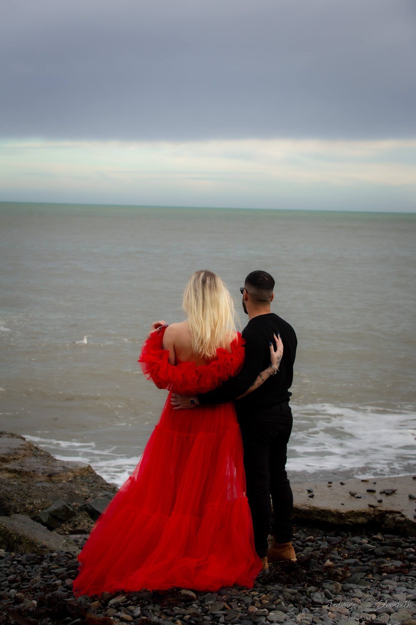 Couple at the water’s edge, seen from behind
