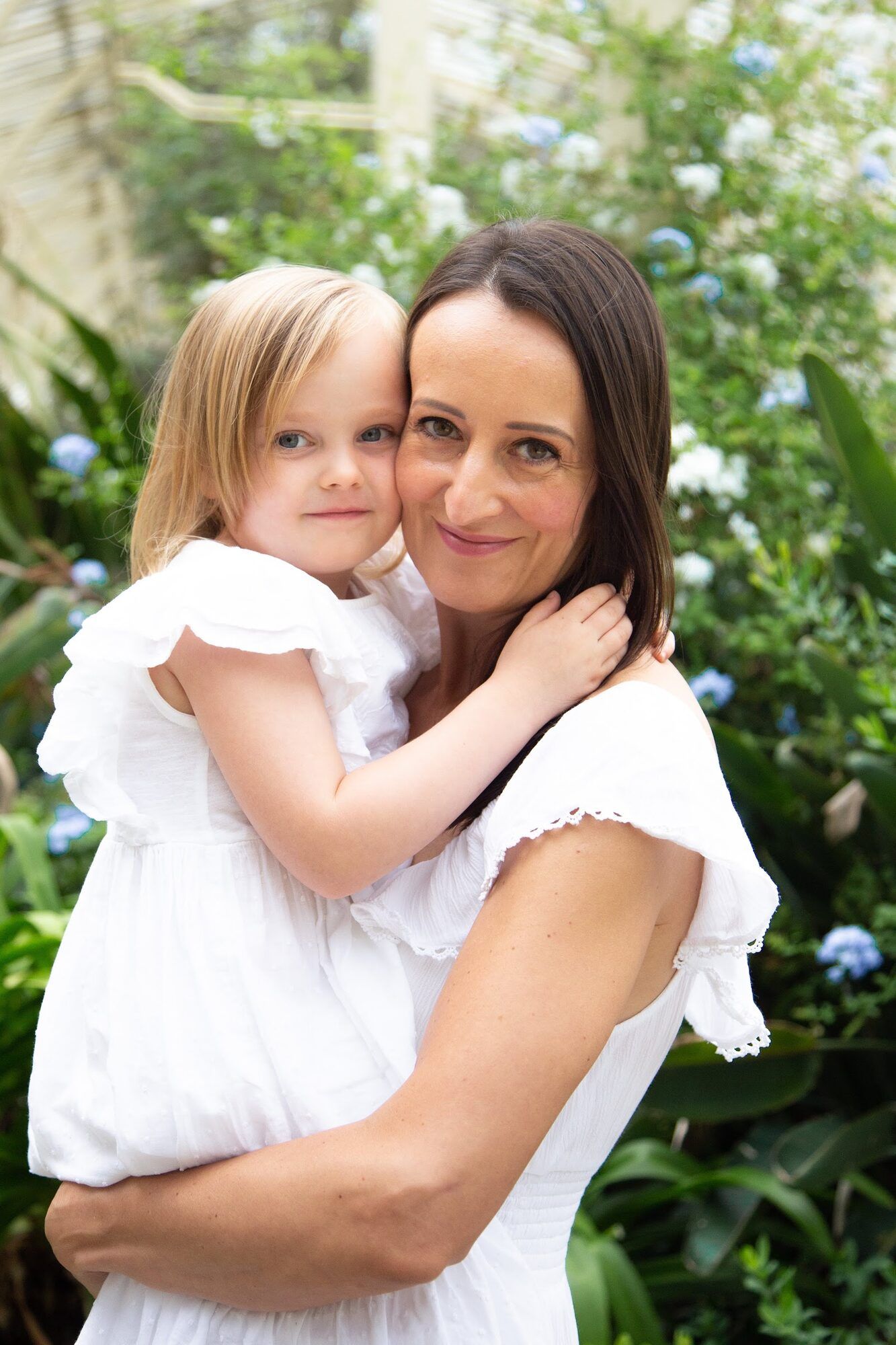 Little girl hugging her mother among hydrangeas