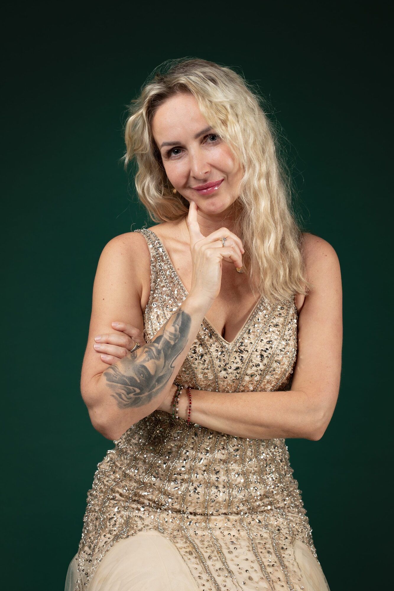 Blonde woman in a gold sequinned dress, green backdrop