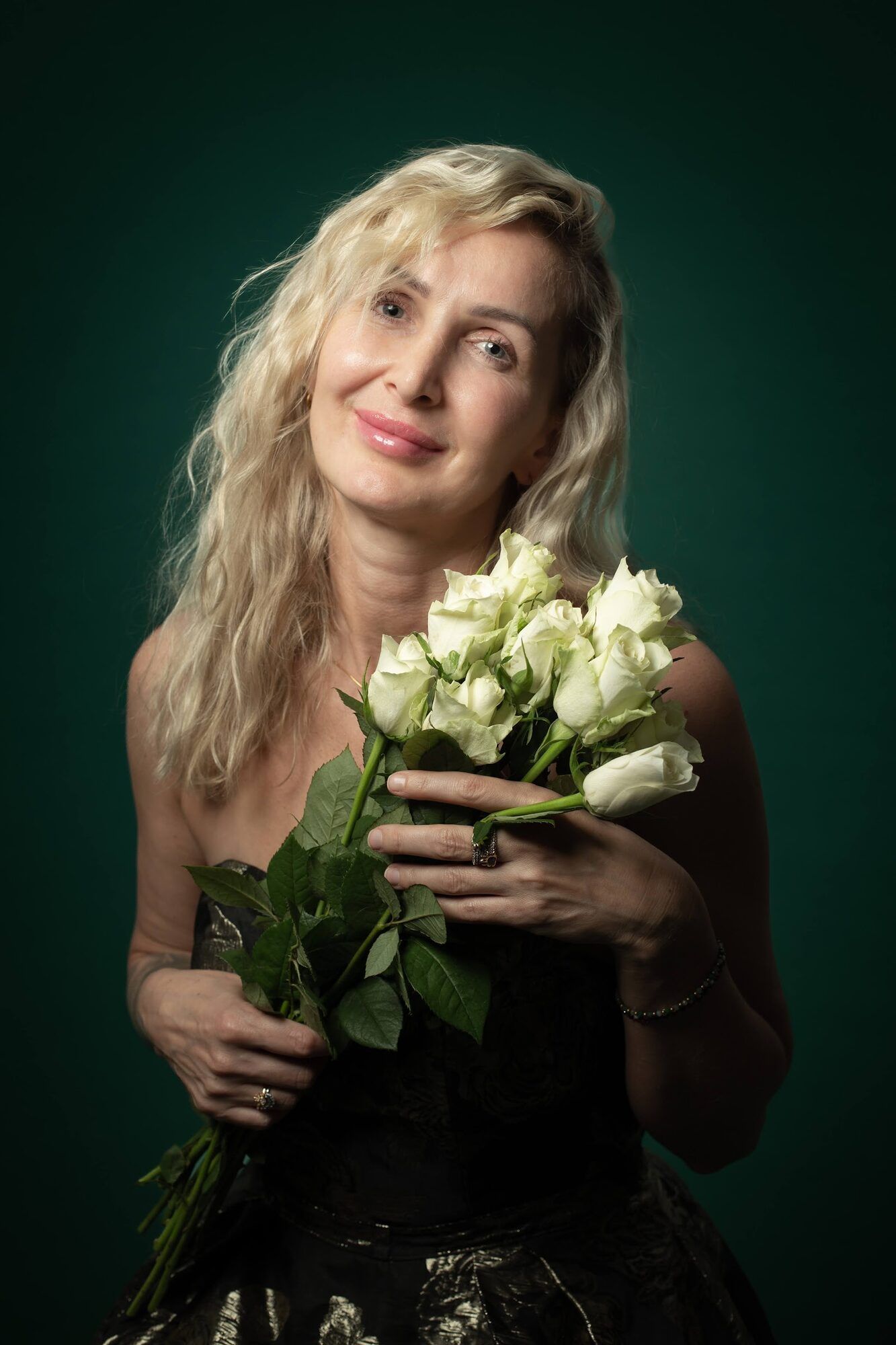 Blonde woman holding white roses, green backdrop