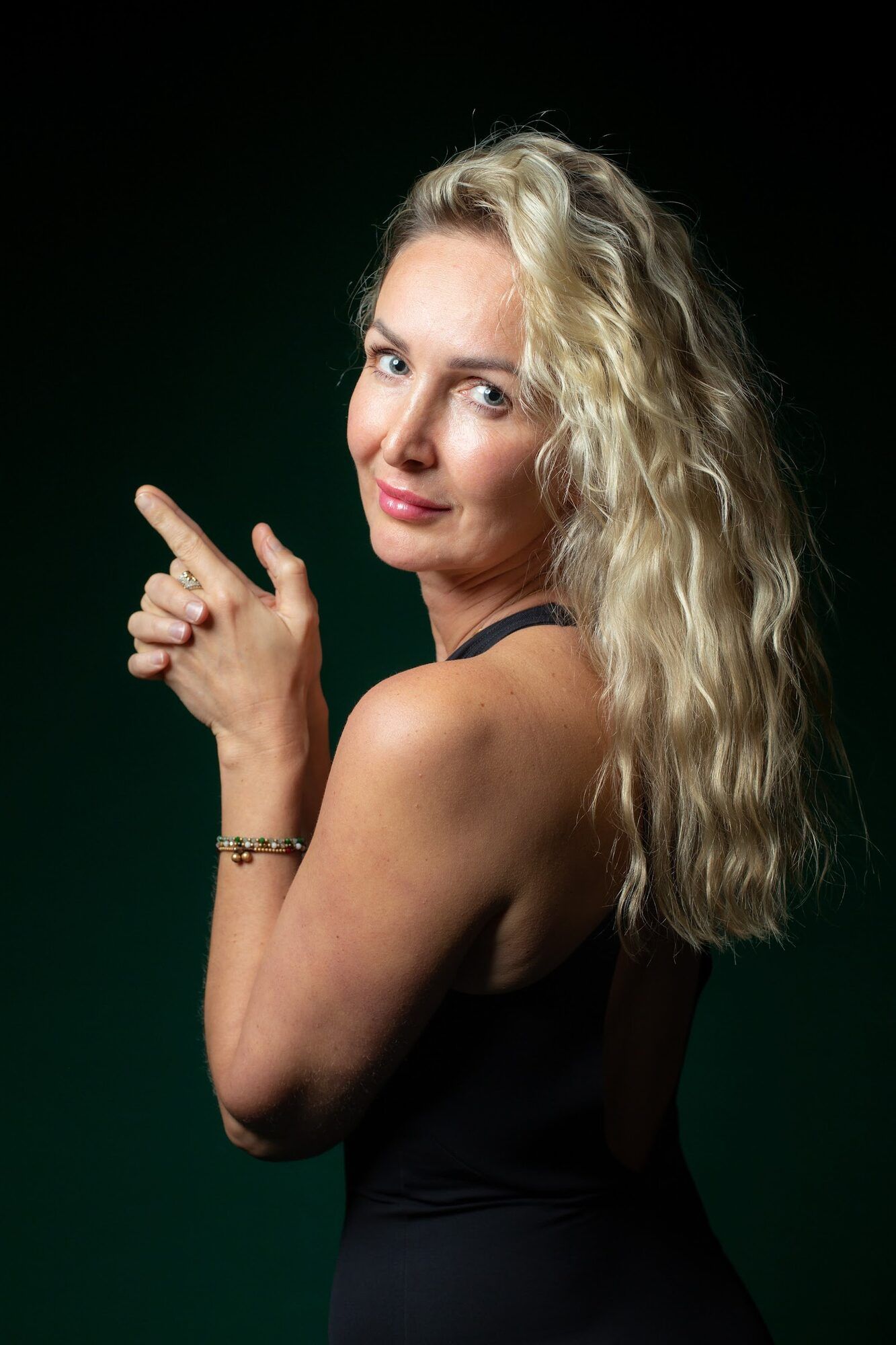 Blonde woman looking over her shoulder, green backdrop