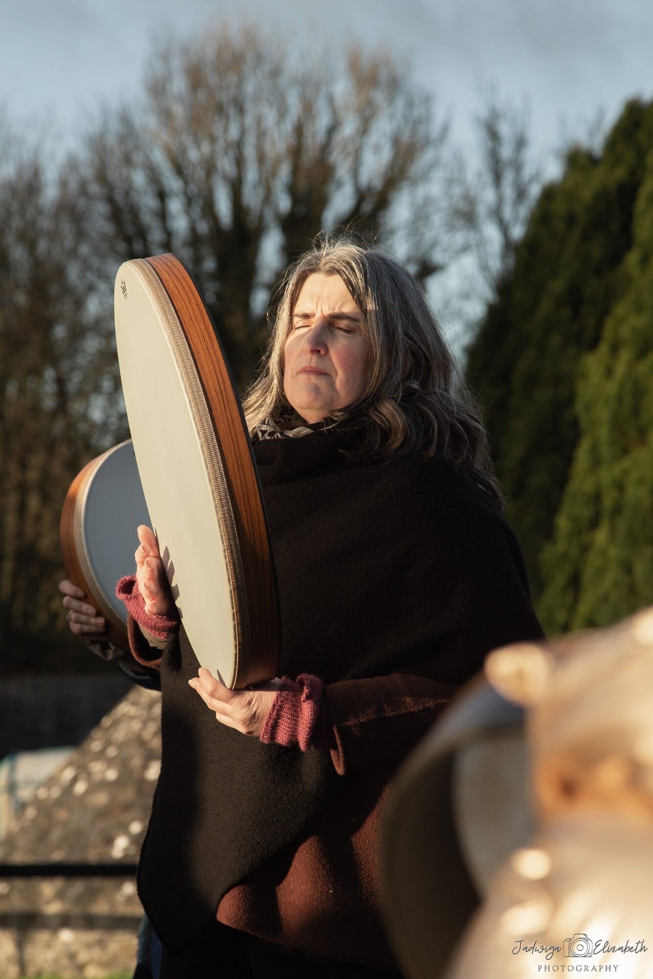 Woman holding a frame drum in winter sun