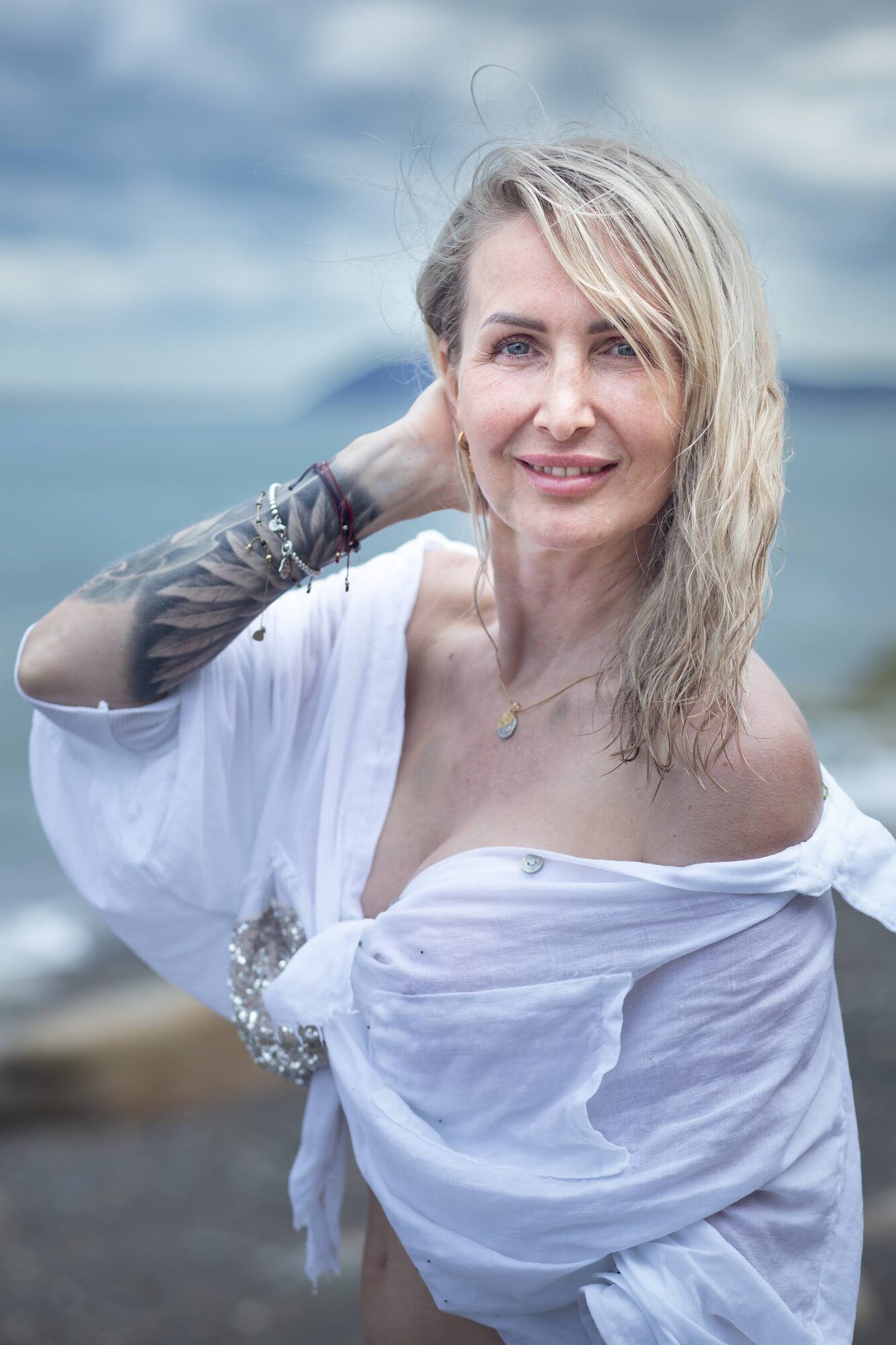 Blonde woman in a white shirt by the sea