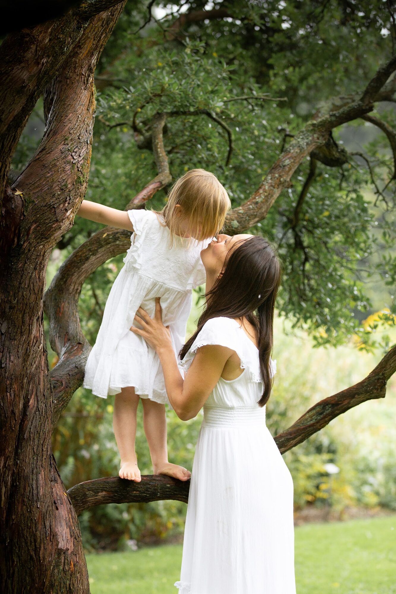 Mother lifting her daughter in a tree