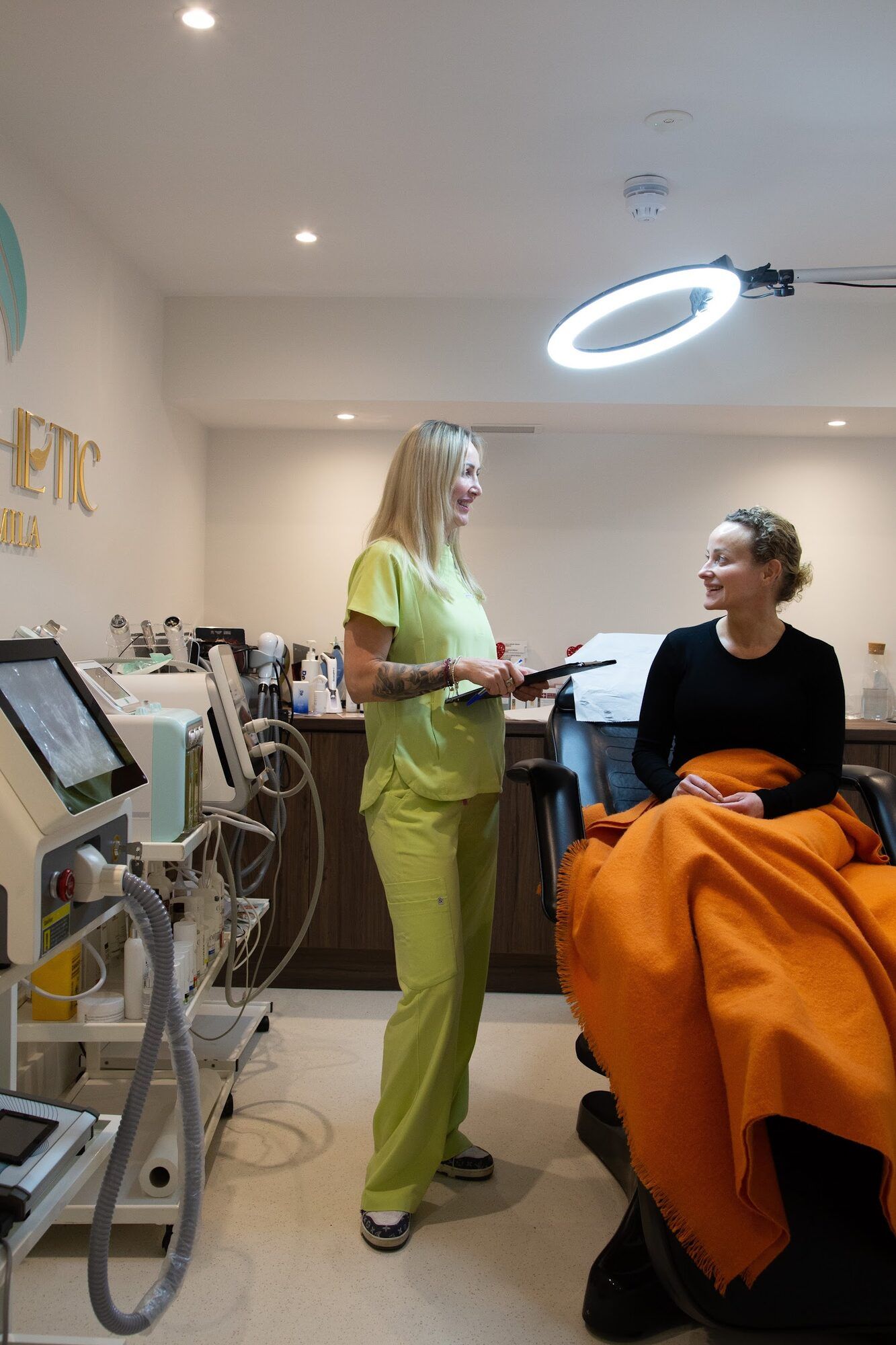 Practitioner with a client in the treatment chair, ring light behind