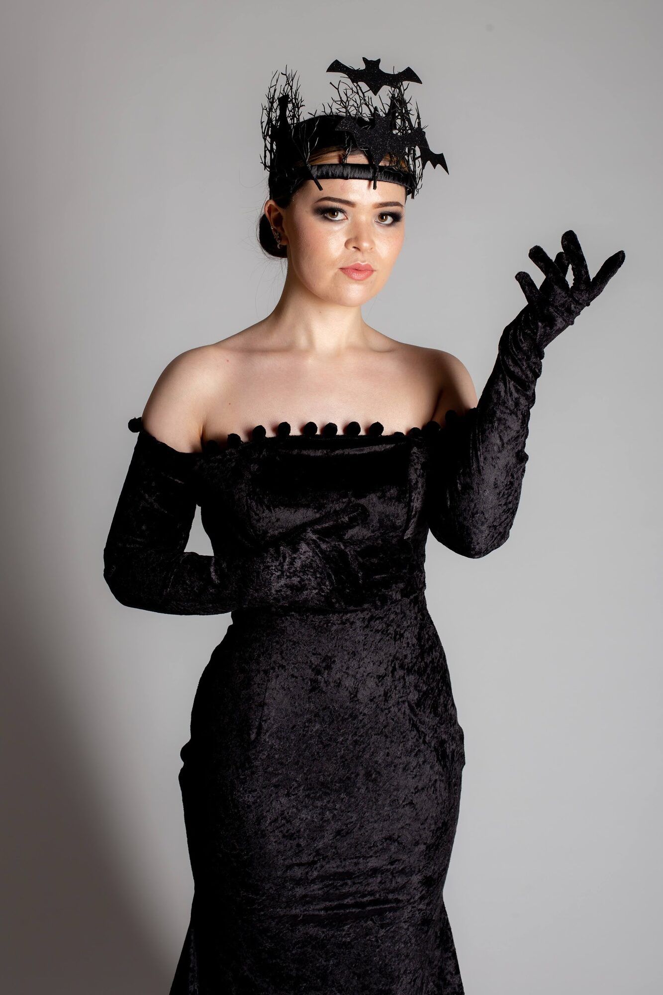 Woman in a bat headpiece and black velvet gown, full length