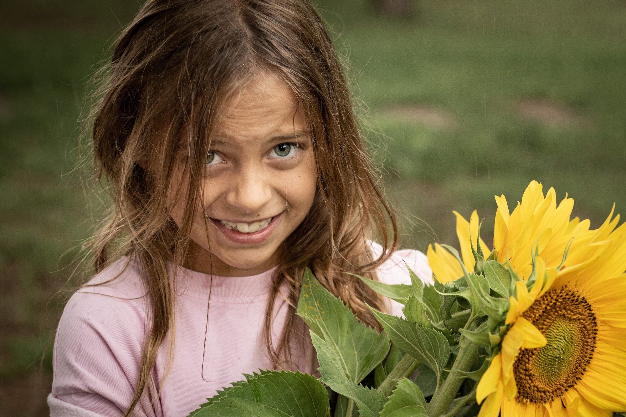 Girl smiling beside a sunflower