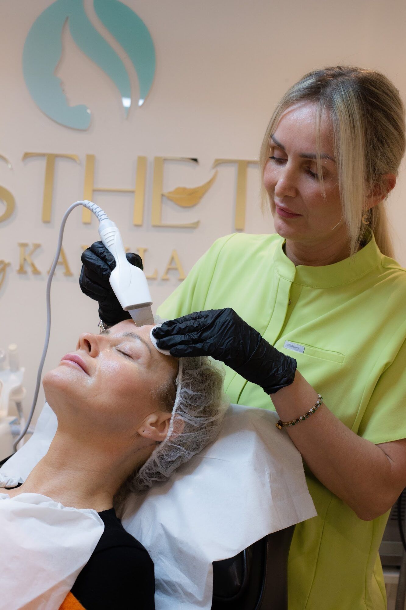 Facial treatment with a handheld device, the clinic logo behind