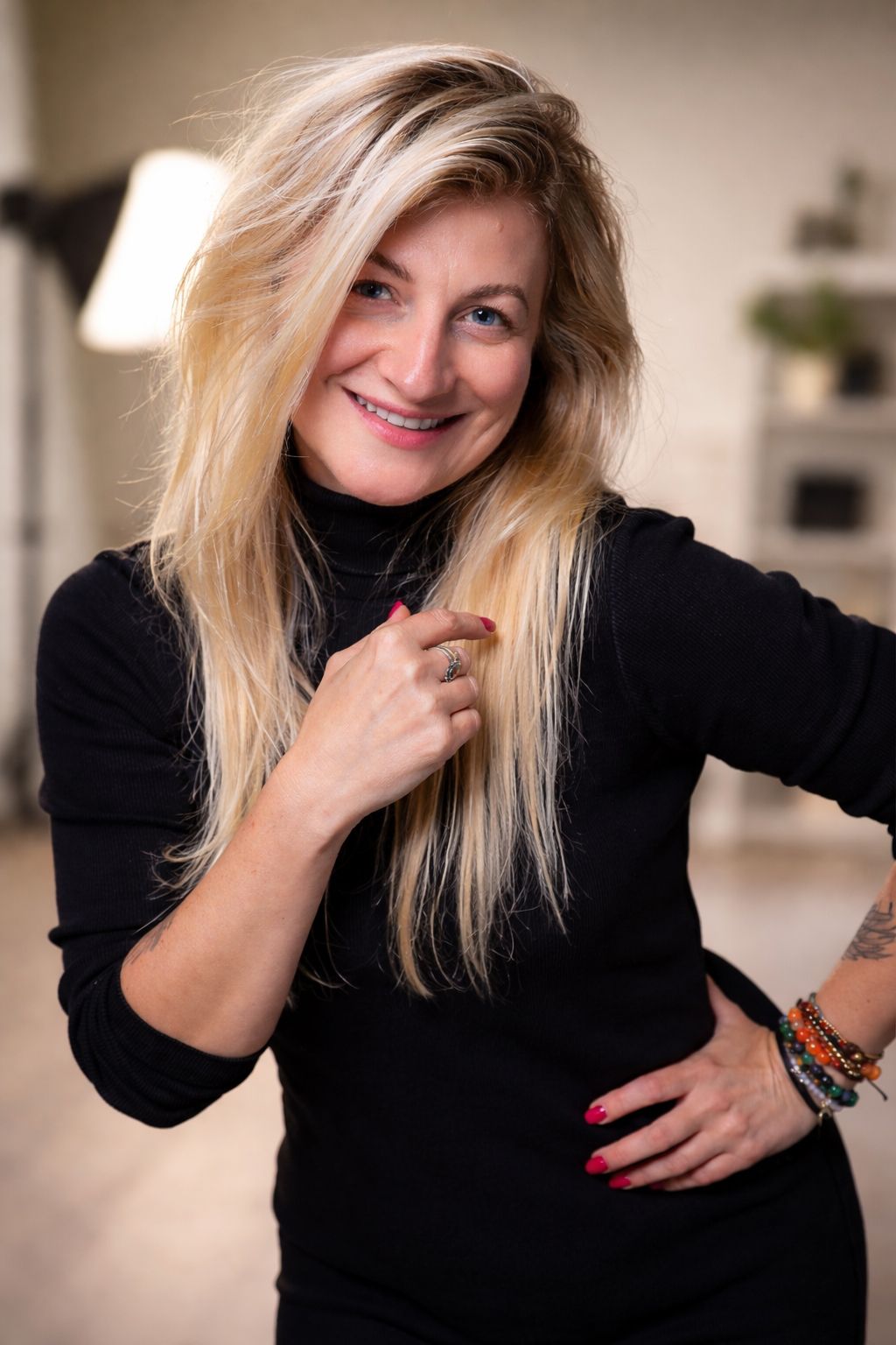 Jadwiga smiling in her studio, in a black turtleneck, one hand on her hip.