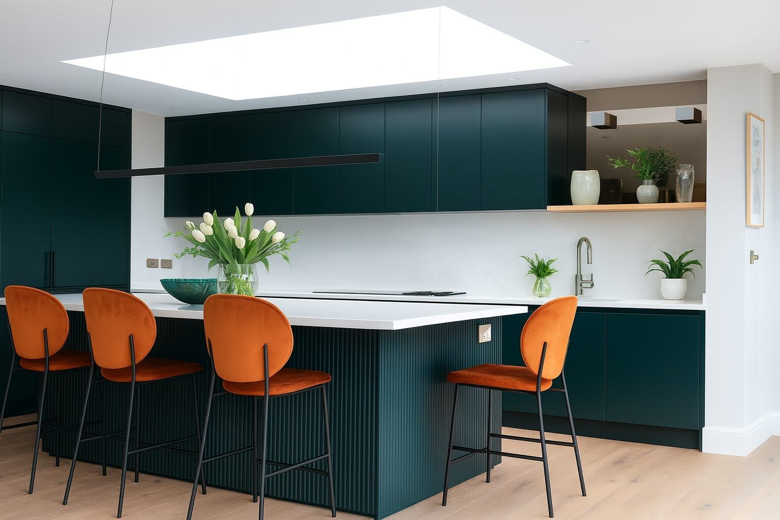 Dark green kitchen with a long island, orange velvet bar stools and a skylight above